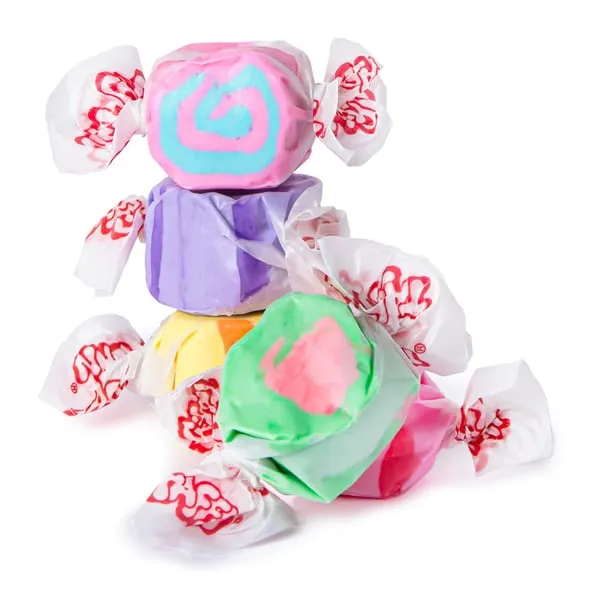 Pieces of Taffy Town salt water taffy in pink, purple, yellow and green, twist-wrapped in white and red paper